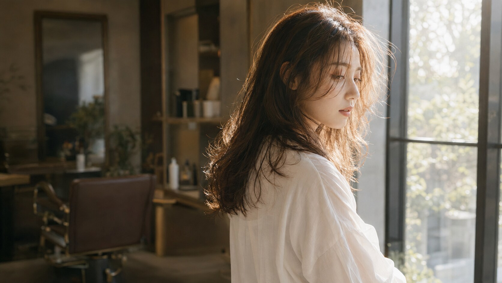 窓辺に立つ女性の柔らかなヘアスタイル